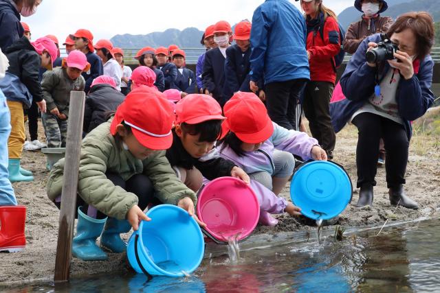 水之上子ども園の園児と水之上小学校の児童がアユを放流